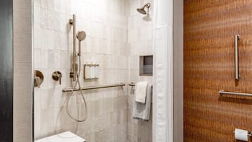 A modern shower area with a glass partition, a handheld showerhead, and a towel rack.