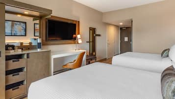 Een hotelkamer met twee bedden, een bureau, een stoel, een televisie en een kledingkast.