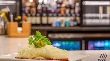 A plate with a food item, a fork, and a bar with bottles in the background.