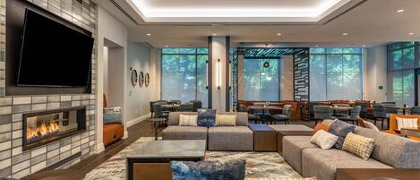 A modern lounge area with a fireplace, comfortable seating, and large windows offering natural light.