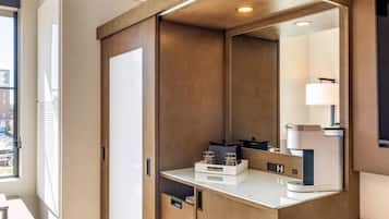 Un baño moderno con un espejo grande, una máquina de café y un mueble pequeño.