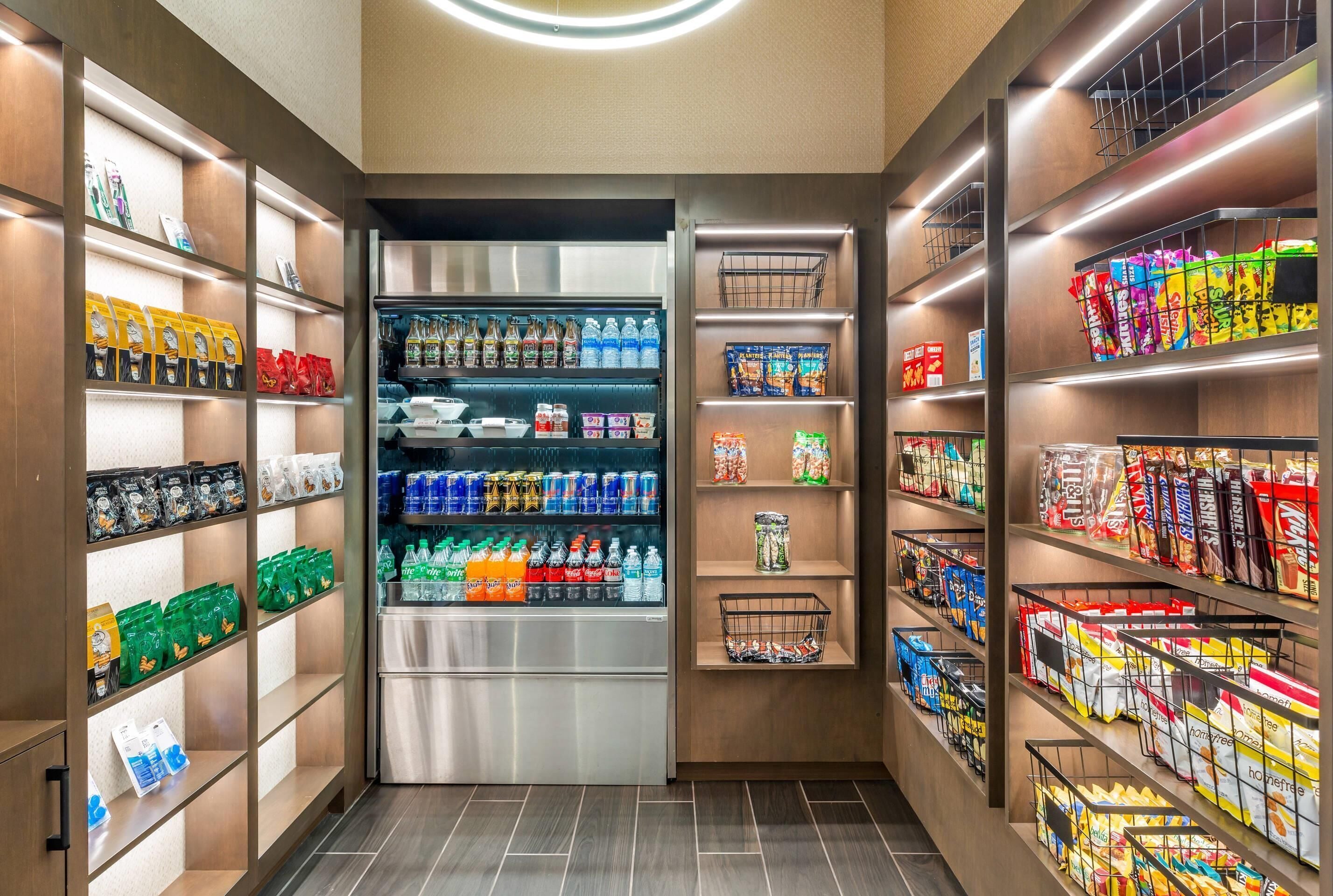 Un supermercado bien organizado con estantes llenos de diversos productos, incluyendo bebidas, aperitivos y alimentos envasados.