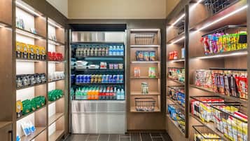 Un supermercado bien organizado con estantes llenos de diversos productos, incluyendo bebidas, aperitivos y alimentos envasados.