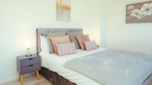 Une chambre à coucher avec un lit, des tables de chevet et des œuvres d’art murales.