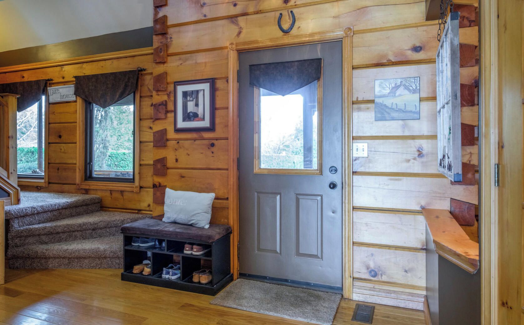 L’intérieur d’une cabane en rondins, avec un banc, un porte-chaussures et une porte dotée d’une fenêtre.