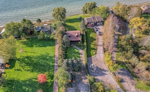 Vista aérea de una zona residencial con un jardín extenso, un camino de entrada y una casa con techo inclinado.