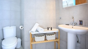 A bathroom with a toilet, sink, and a shelf with baskets. - Villa With 180 Degree Sea View - Sleeps 2-6 (Malevizi)