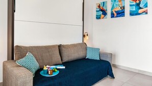 A modern living room with a sofa, a coffee table with snacks, and three wall-mounted artworks.