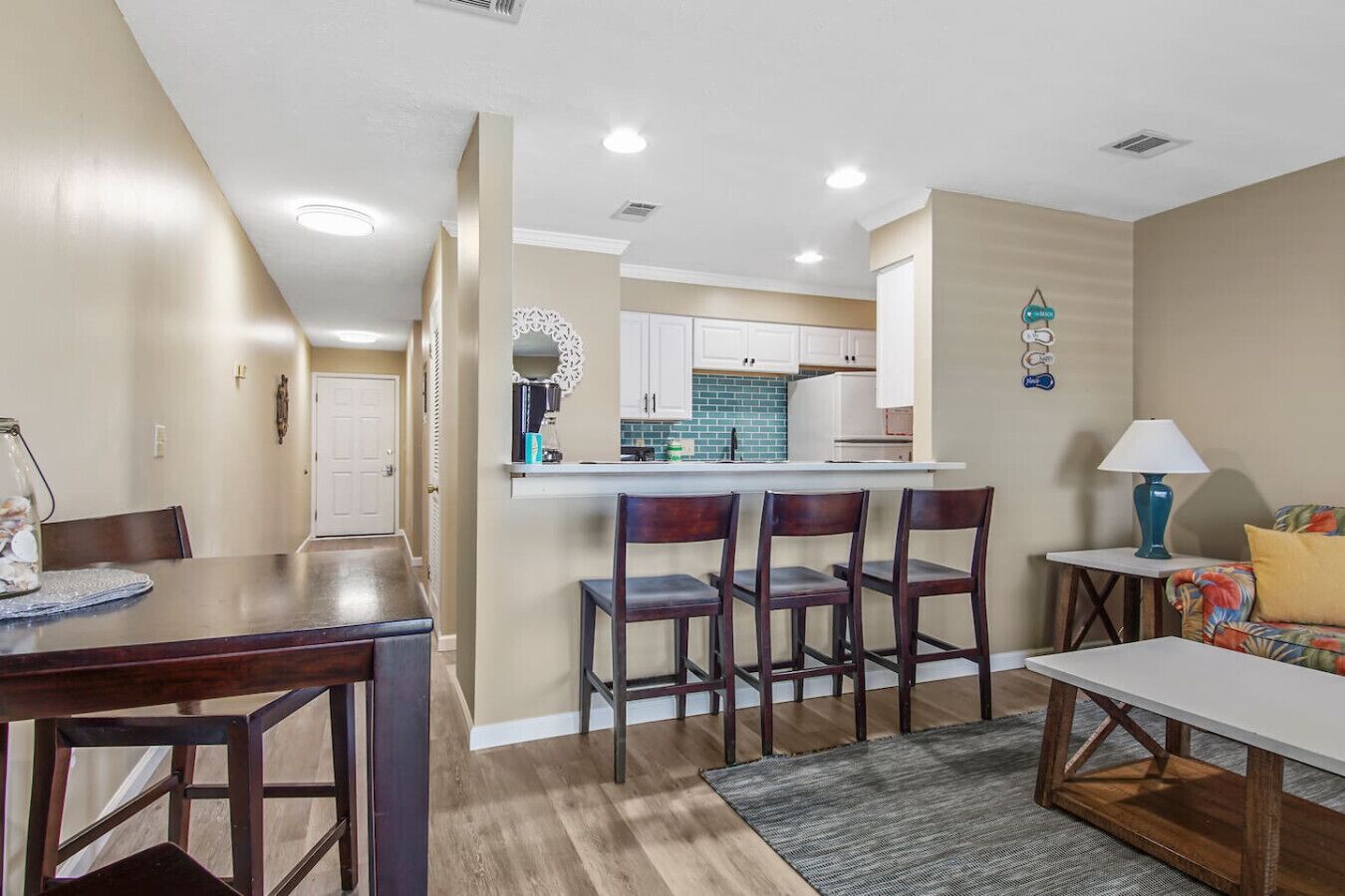 A modern kitchen with white cabinets, a central island, and a dining area with a wooden table and chairs.