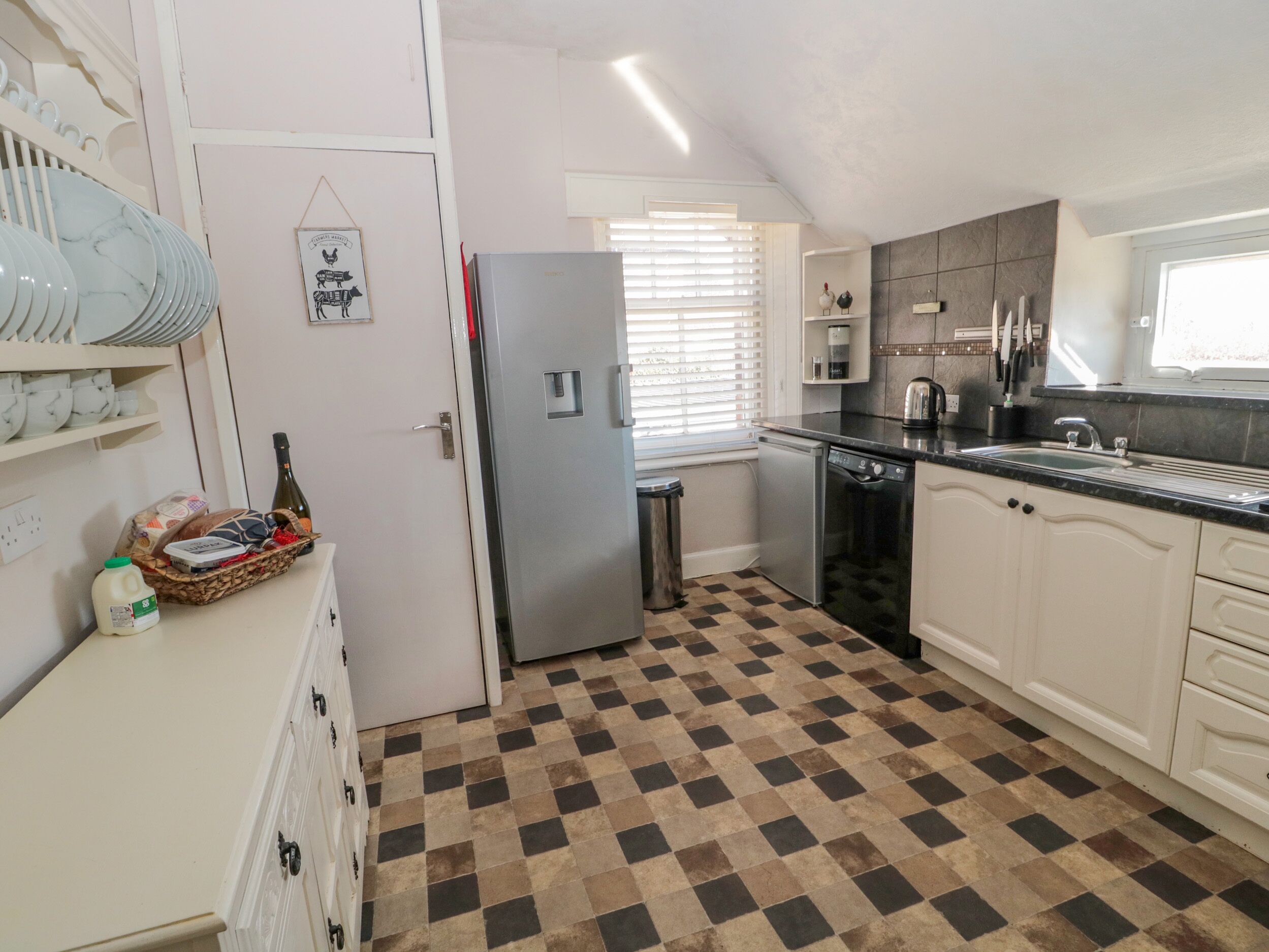 Cocina compacta con refrigerador, lavavajillas y piso de cuadros.