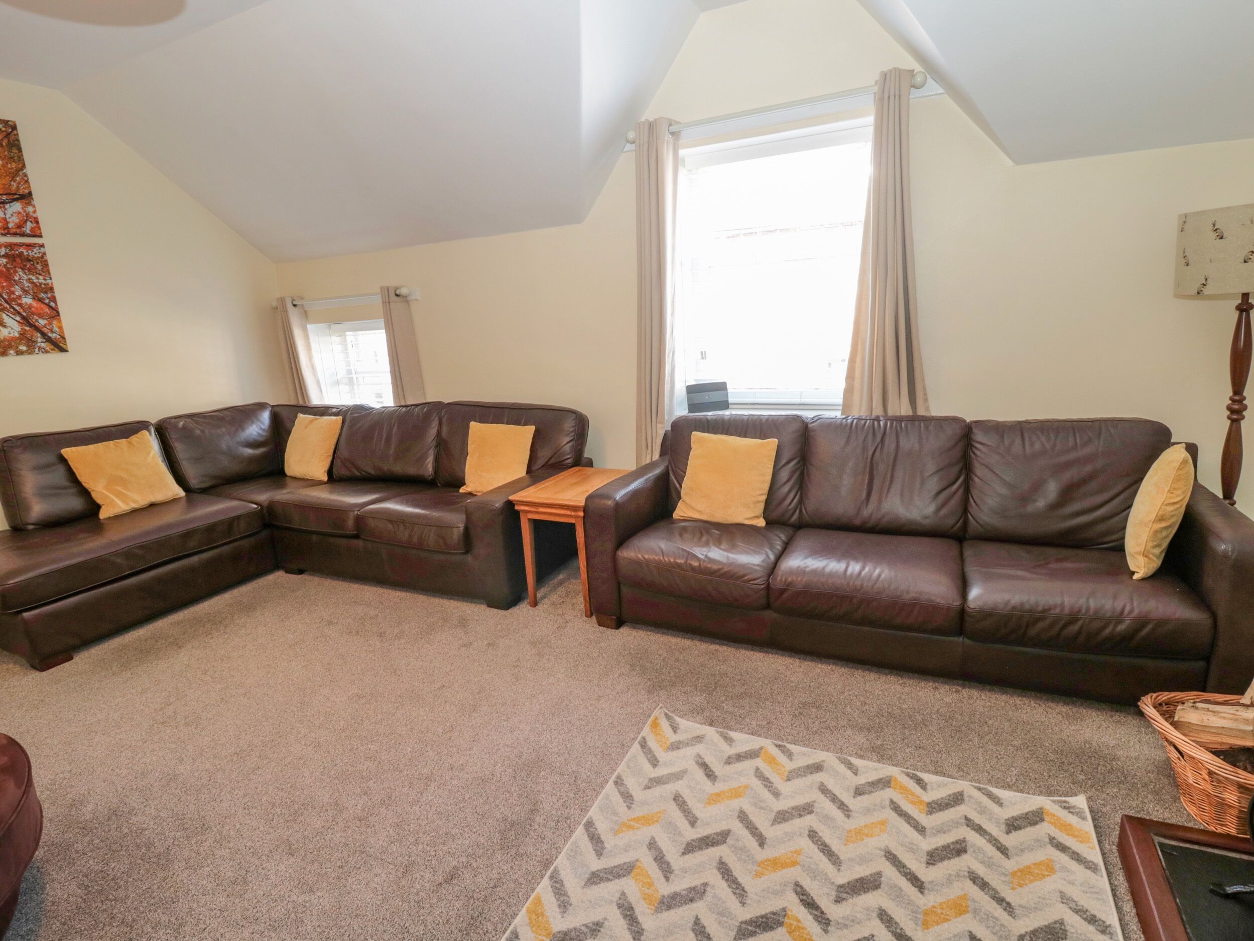 A living room with two brown leather sofas, a wooden coffee table, and a patterned rug.