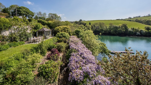 Un jardin agrémenté d’un belvédère, d’une rivière et d’une végétation luxuriante.