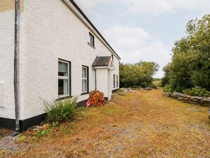 A white building with a gravel driveway and a stone wall. - Kealduff Lower (Glenbeigh)