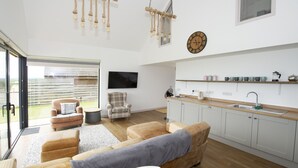 Un saló modern amb un sofà, una taula de menjador i una zona de cuina amb un rentaplat i prestatges.