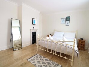 Un dormitorio con una cama con dosel blanca, un espejo, una chimenea y una mesita de noche con una lámpara.