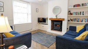 A living room with a fireplace, a television, a bookshelf, and two sofas. - Springfield (Fakenham)