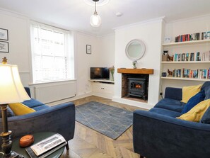 A living room with a fireplace, a television, a bookshelf, and two sofas.