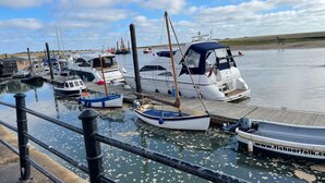 A marina with several boats docked, a wooden pier, and calm water. - Springfield (Fakenham)