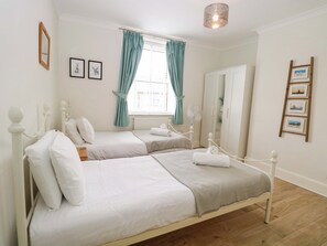 Habitación doble con dos camas, una ventana con cortinas, un ventilador y un armario.