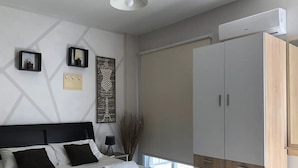 A modern bedroom with a large bed, a wardrobe, and a wall-mounted air conditioner.