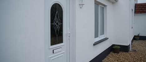 A white house with a decorative glass door, a small window, and a potted plant.