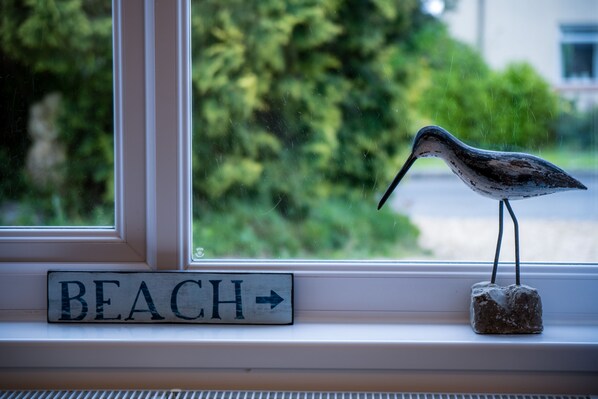 A bird figurine on a windowsill with a 'BEACH' sign below it. - Shorelands - 1 Bedroom - Manorbier (Tenby)