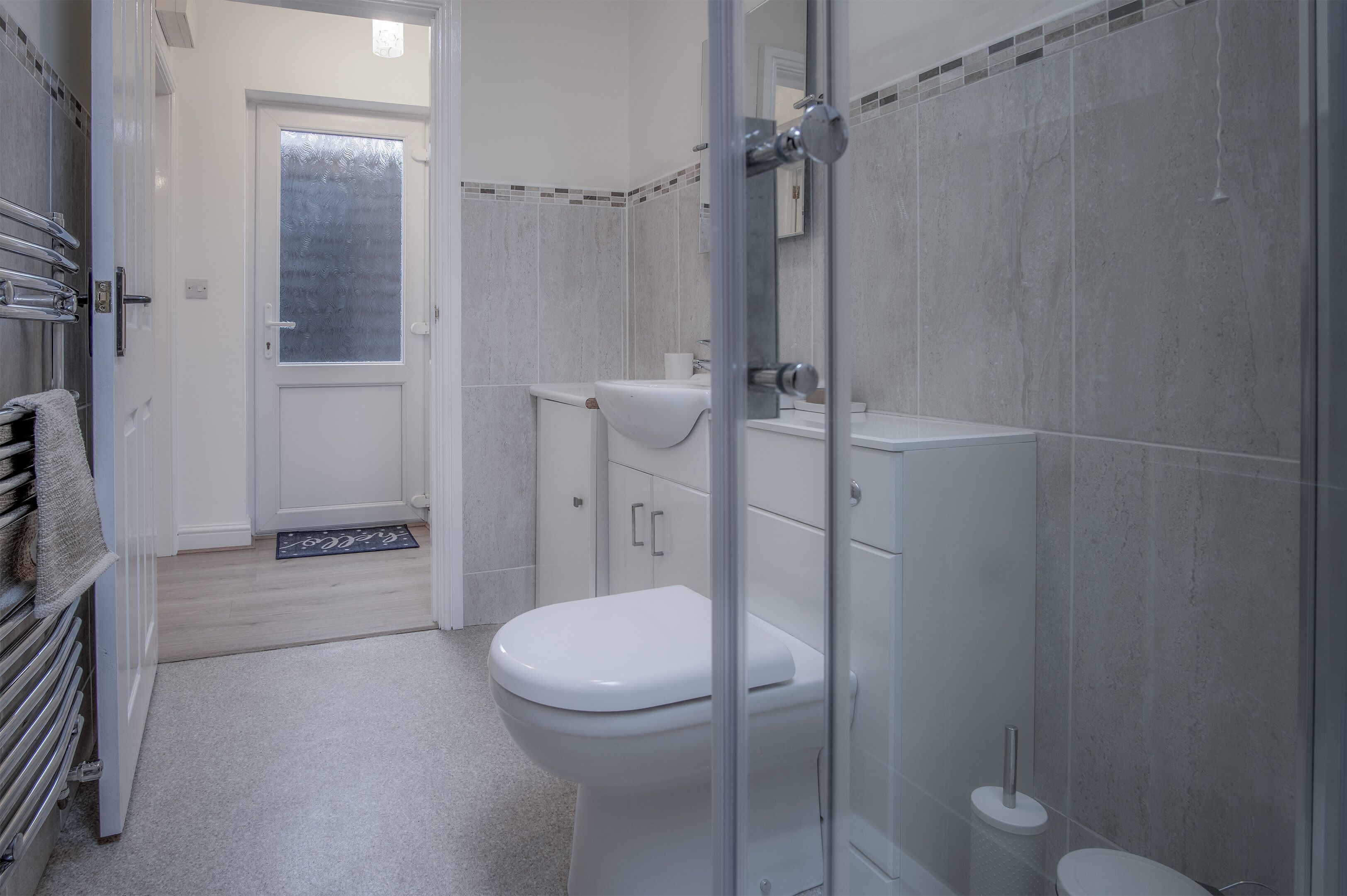 A modern bathroom with a white toilet, a glass shower enclosure, and a tiled shower area.