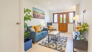 A modern living room with a blue sofa, a grey armchair, a coffee table, and a patterned rug.