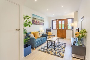 A modern living room with a blue sofa, a grey armchair, a coffee table, and a patterned rug.