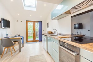 A modern kitchen with a built-in oven, a dishwasher, and a large window above the sink.