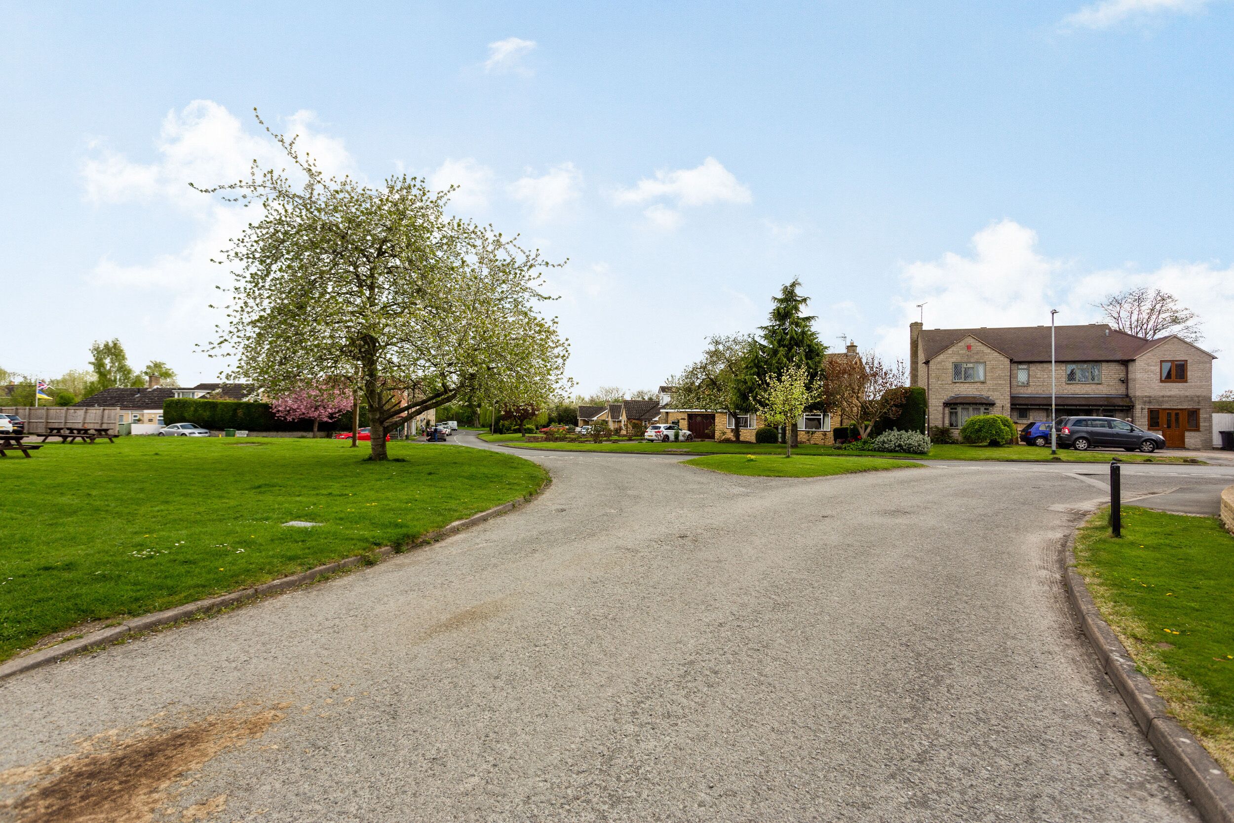 A residential street with houses, a grassy area, and a clear sky.