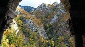 Une arche en pierre encadrant une vue sur un paysage montagneux aux couleurs automnales.