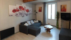 Un salon moderne avec un canapé d’angle, une table basse ronde en bois et des œuvres d’art accrochées aux murs.