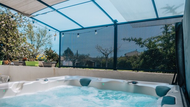 A hot tub with a mesh roof, surrounded by potted plants and a view of the outdoors. - Le Titibu: Gîte and Spa between Ardèche and Provence, ideal for two (Saint-Paulet-de-Caisson)