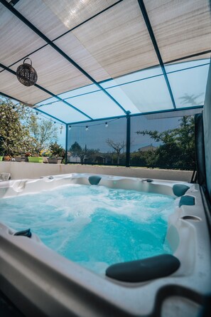 Un bain à remous doté d’un toit en treillis, entouré de plantes en pot et offrant une vue sur l’extérieur.