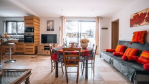 A modern kitchen with built-in appliances, a dining area with a round table and chairs, and a cozy living space with a sofa and vibrant cushions. - Le Titibu: Gîte and Spa between Ardèche and Provence, ideal for two (Saint-Paulet-de-Caisson)