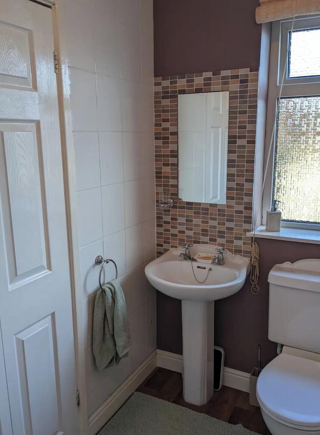 Une salle de bain avec un lavabo blanc, un miroir et des toilettes.