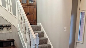 Eine Treppe mit Teppichstufen, weißen Spindeln und einer Holztür mit Glasfeldern.
