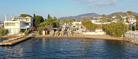 Una zona costera con un puerto deportivo, edificios modernos y una playa.