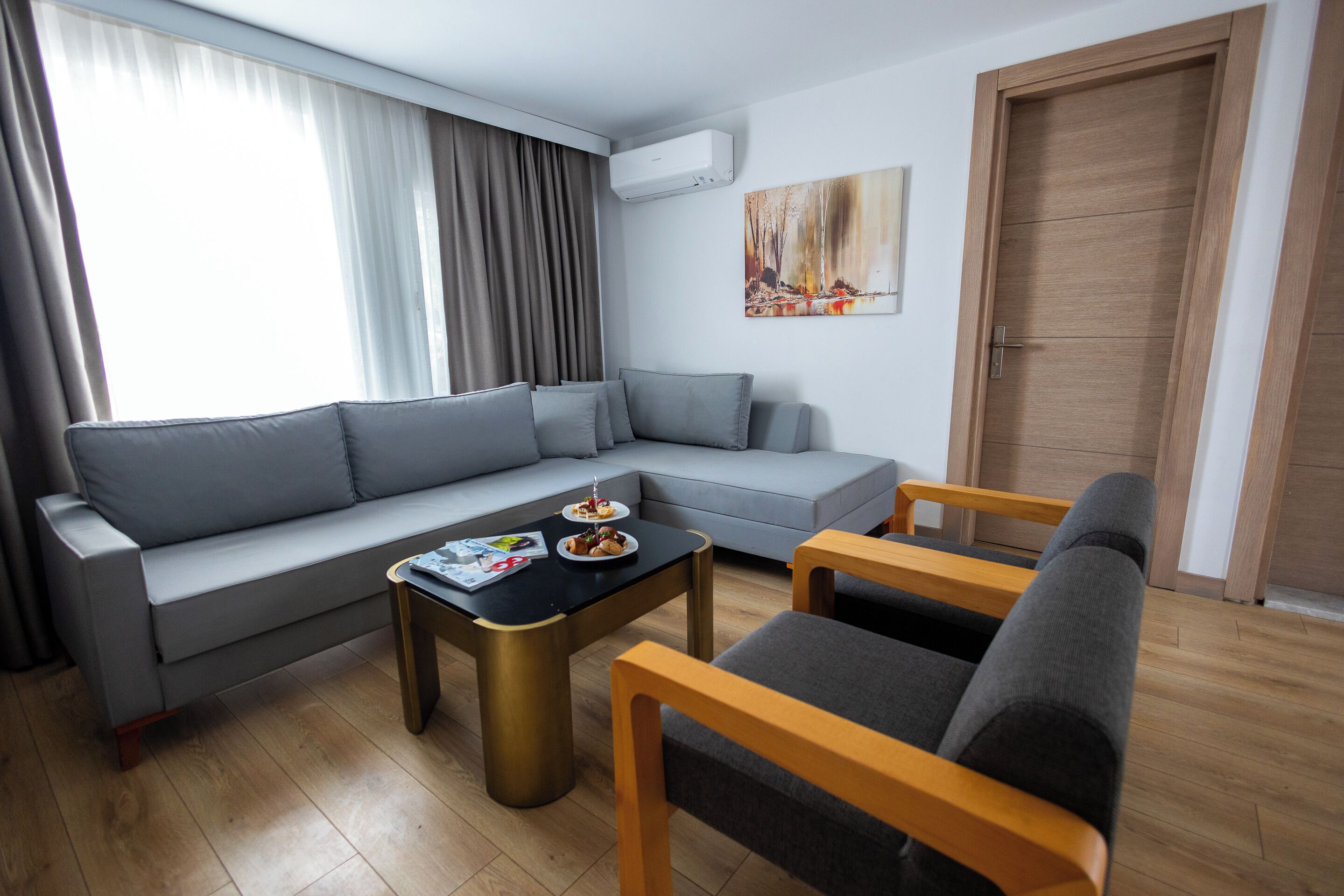 A modern living room with a grey sofa, a coffee table, and two wooden chairs.