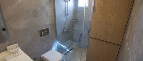 Une salle de bain moderne avec une douche à parois de verre, des toilettes blanches et un meuble en bois.
