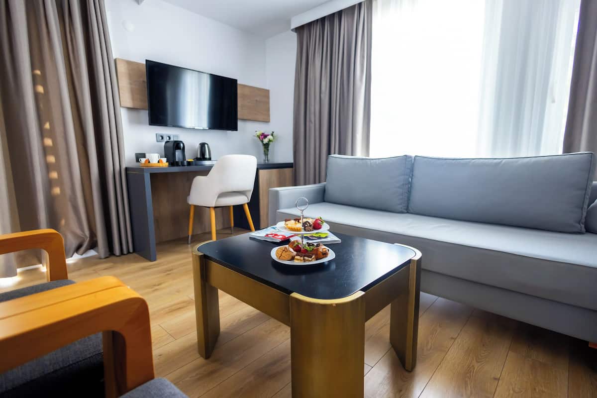 A modern living room with a grey sofa, a wooden coffee table, and a dining area with a small table and chairs.