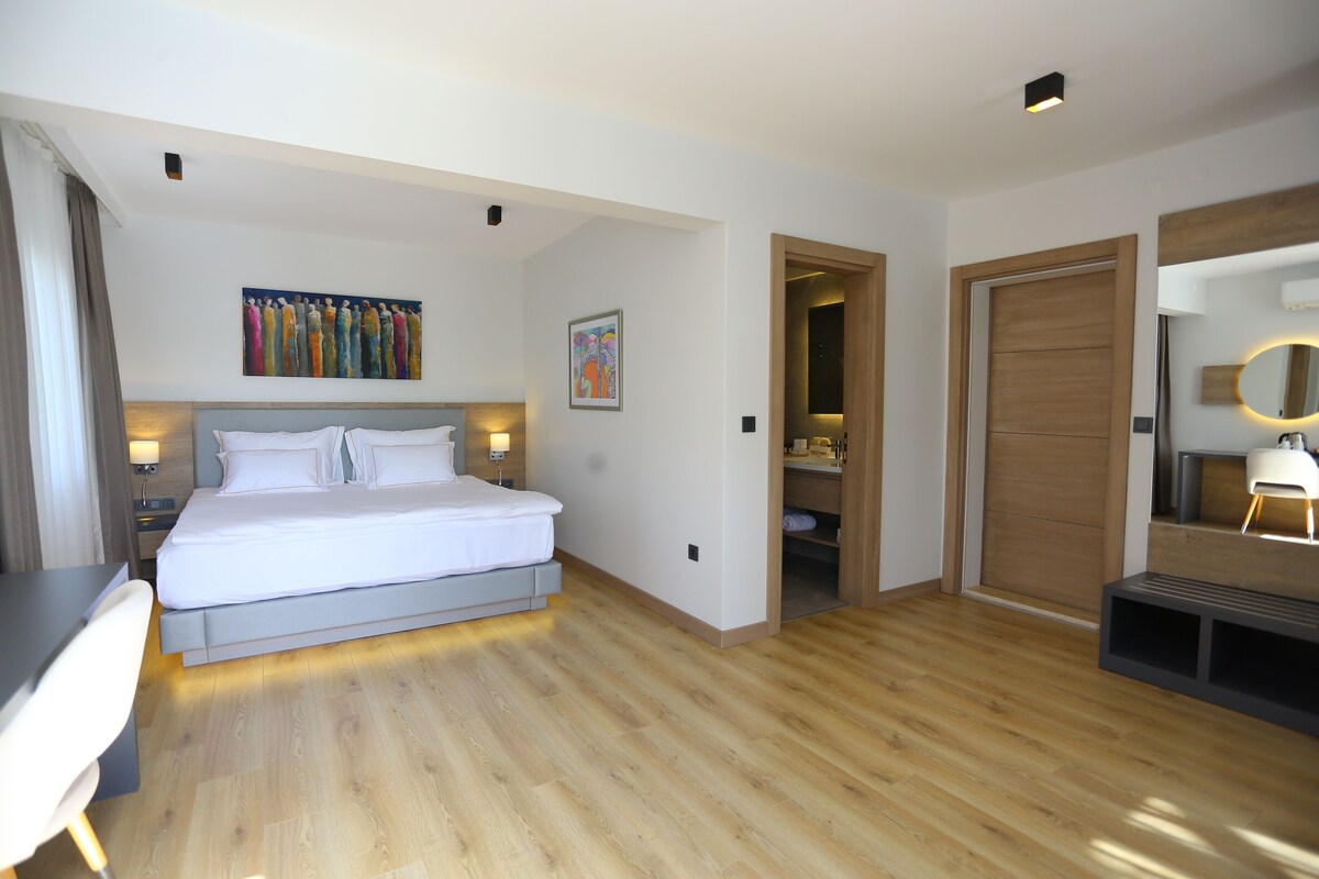 Une chambre d’hôtel comprenant un lit, des tables de chevet, une armoire, un miroir et des œuvres d’art accrochées aux murs.