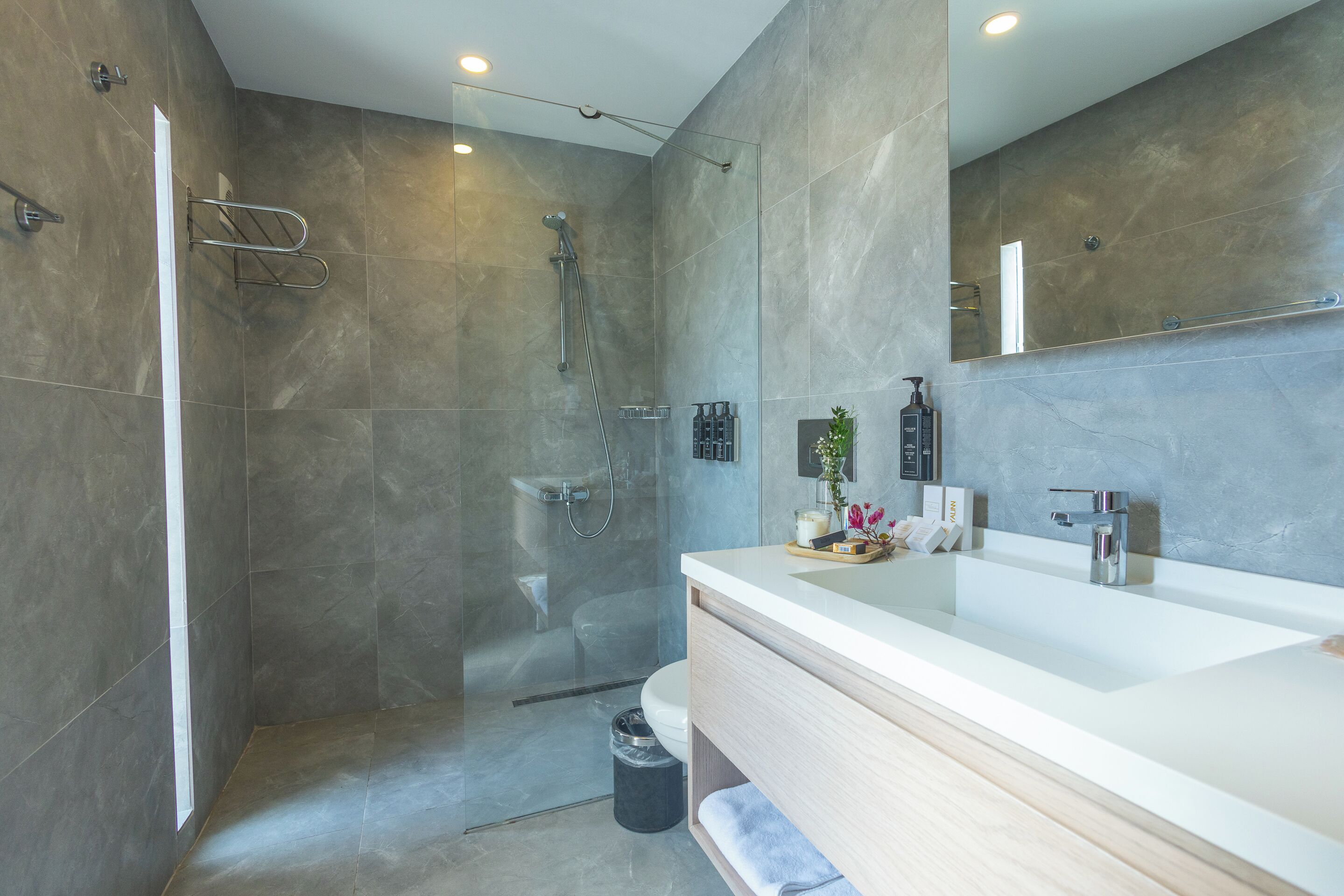 Une salle de bain moderne dotée d’un grand miroir, d’une douche à l’italienne et d’un meuble-lavabo.
