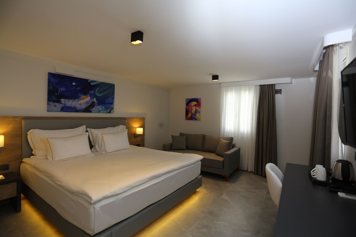 Une chambre d’hôtel avec un grand lit, un canapé, un bureau et une télévision.