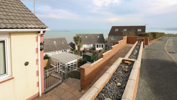 Un barrio residencial con casas, un sendero pavimentado y vistas al mar.