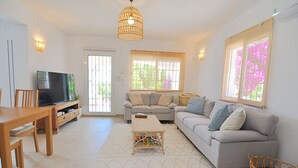 Una sala de estar con sofá, televisión, mesa de madera y alfombra estampada.