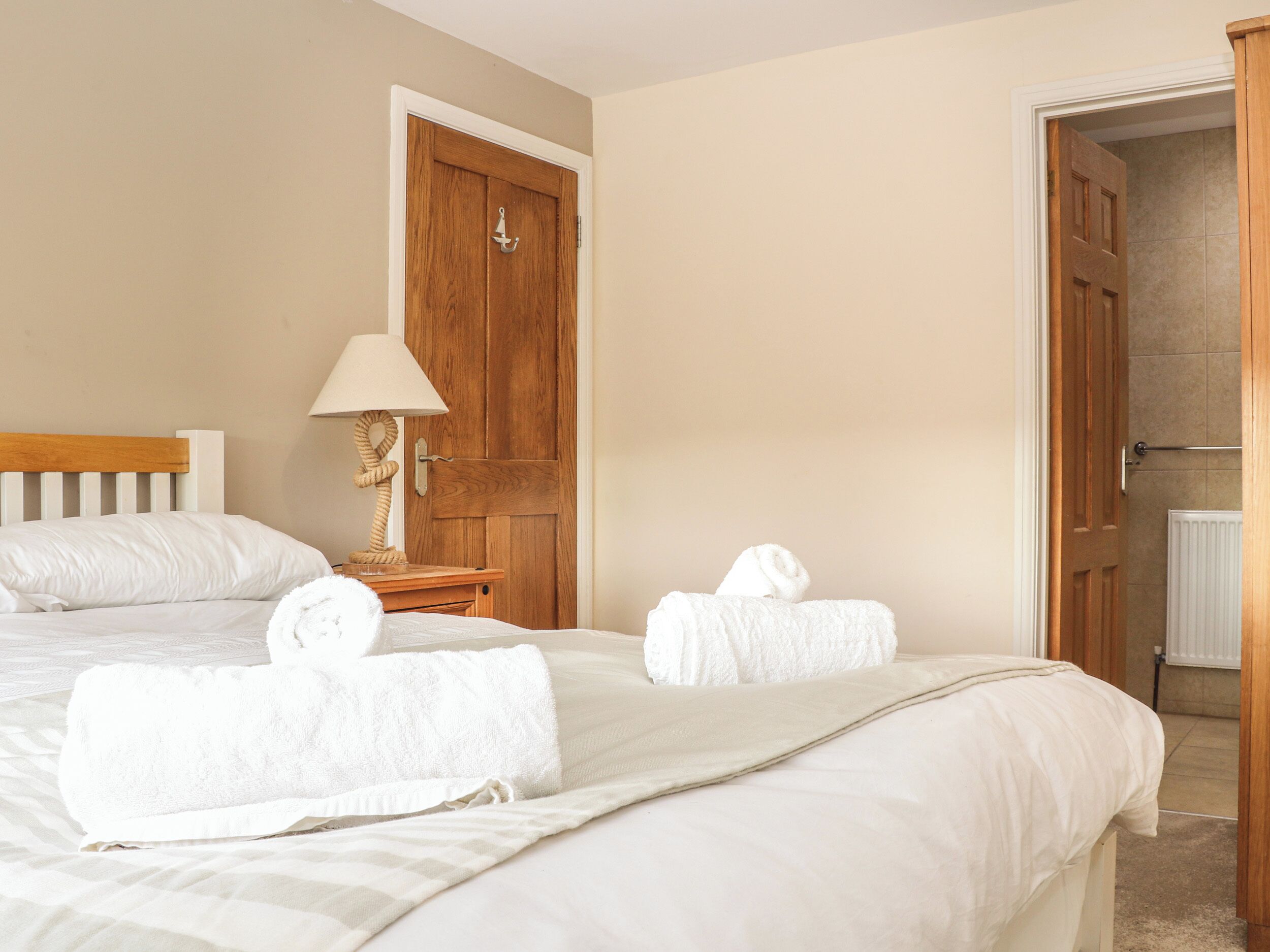 A neatly made bed with white linens and two towels placed on it.