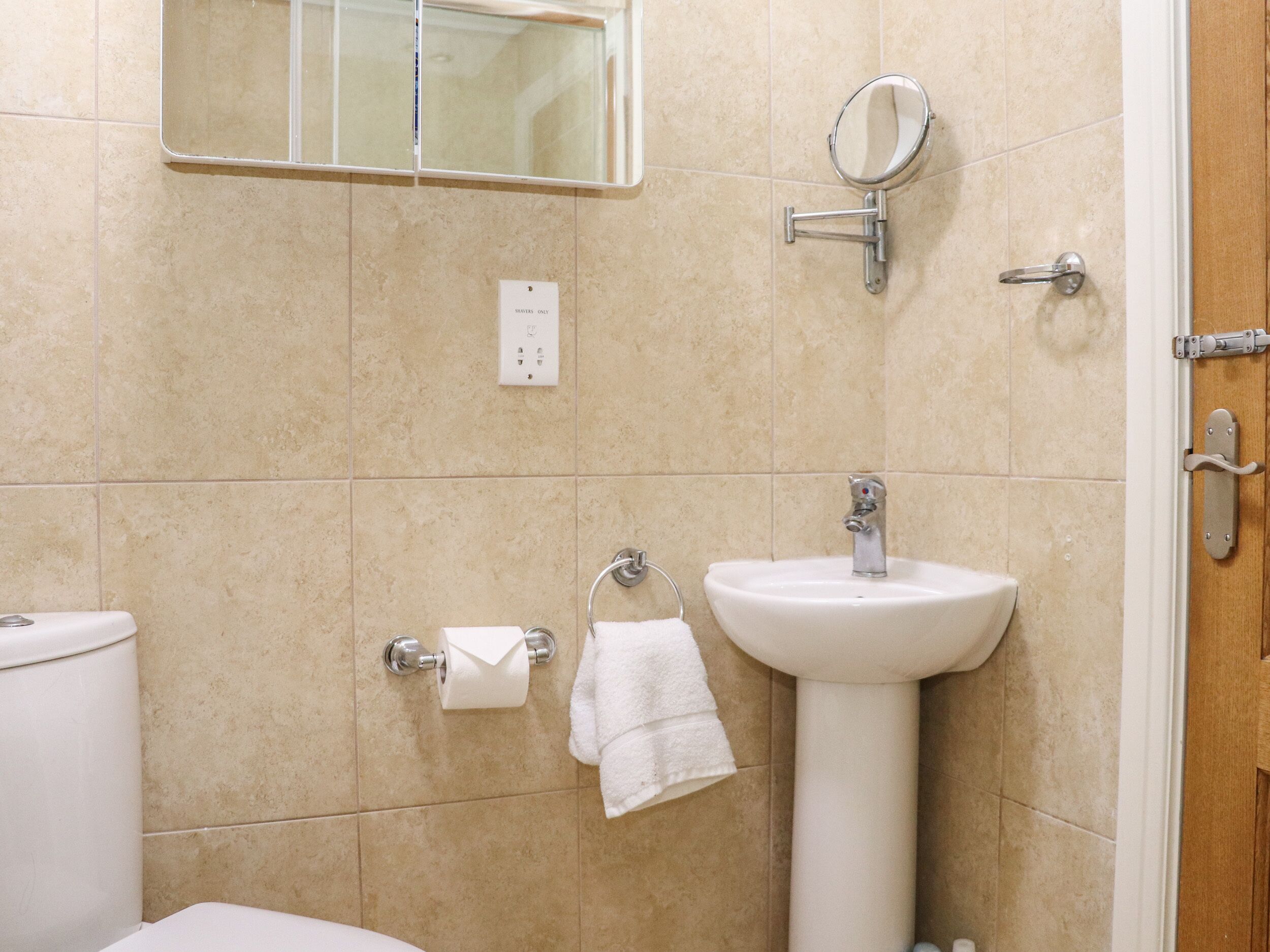 Een badkamer met toilet, wastafel en spiegel.