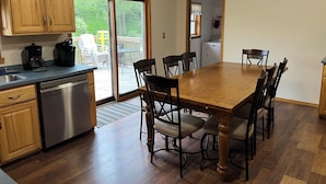 A kitchen with wooden cabinets, a dishwasher, and a dining area with a table and chairs. - Private vacation house for larger groups near the Dells with heated game room. (Reedsburg)